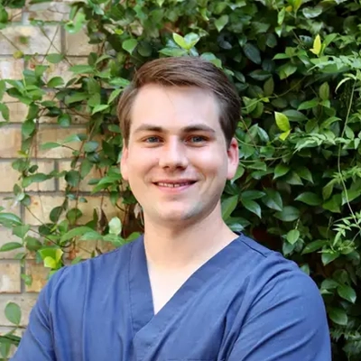 Chiropractor Tyler W. Wright Smiling Outdoors In Front Of Bricks
